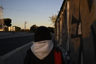 Sunset road scene with a blurred figure walking beside a wall of shadows